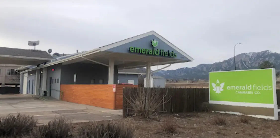 The Emerald Fields dispensary on South Boulder Road, its green sign and covered entrance set against the Flatirons.